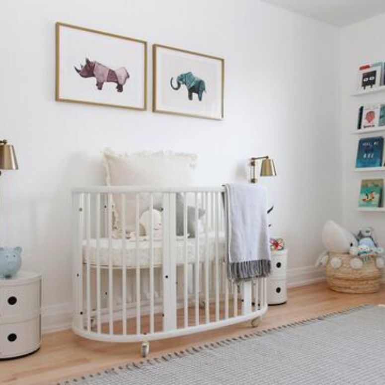 gender-neutral baby room with white walls, brass fixtures and round crib.